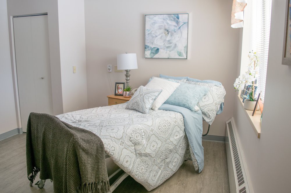A cozy bedroom with minimalist decor, featuring a neatly made bed, a lamp on the bedside table, and a piece of artwork on the wall.