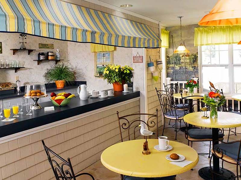 A cozy cafe interior with yellow tables and decorative plants.