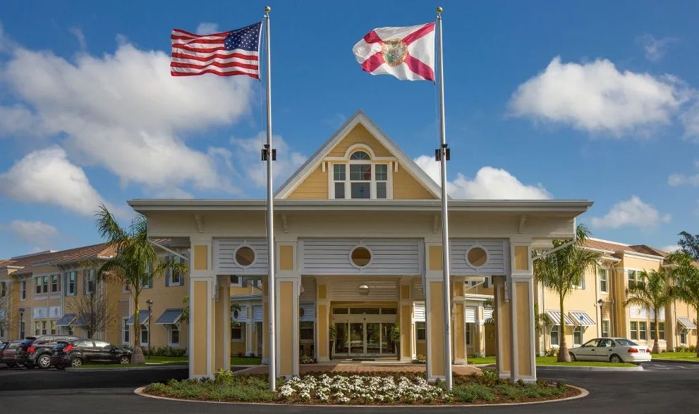 A building entrance with the United States and Florida state flags flying prominently.