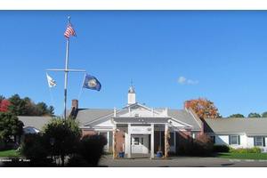 A building with multiple flags displayed in front under a clear blue sky.