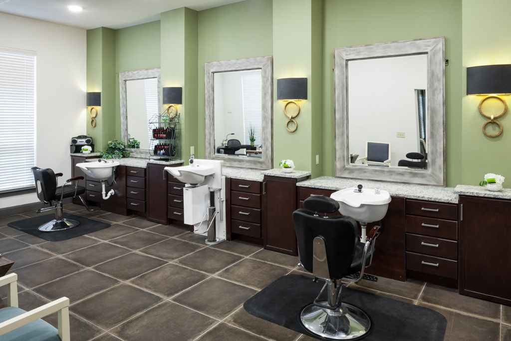 A modern barbershop interior with chairs, mirrors, and sinks.
