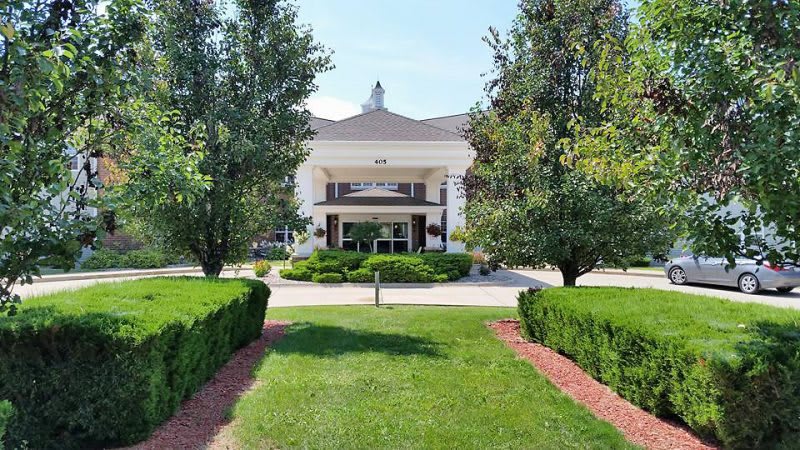 A well-maintained building entrance surrounded by lush greenery and manicured landscaping.