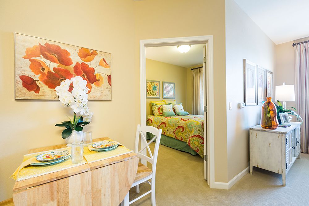 A cozy apartment interior with a small dining area leading into a bedroom.
