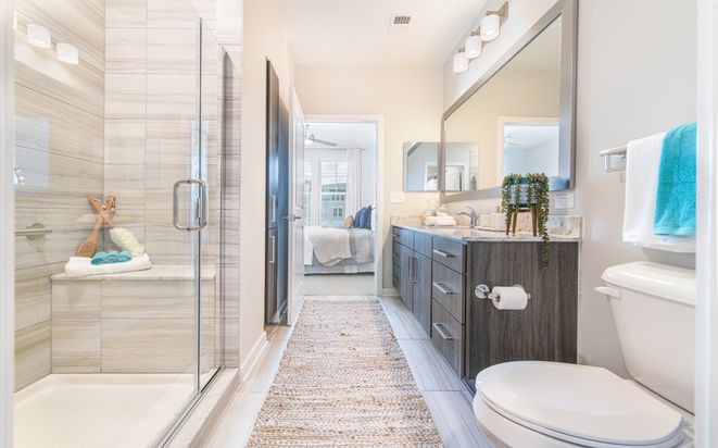 A modern and spacious bathroom with a glass shower, sleek vanity, and large mirror.