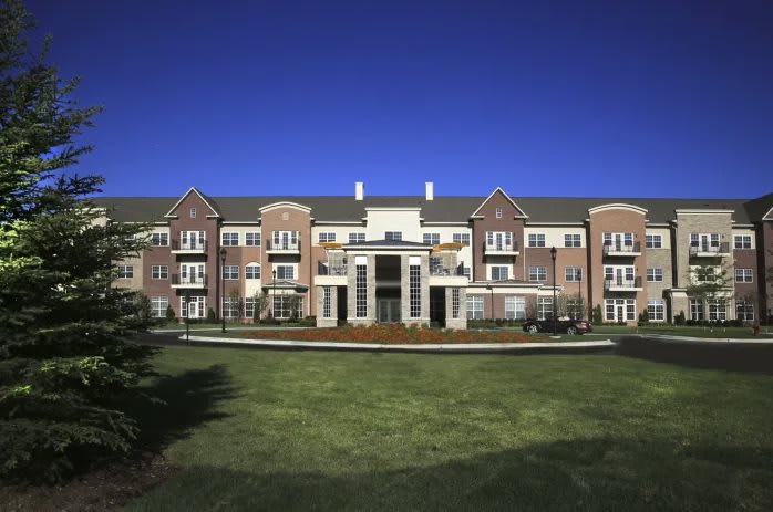 A large residential building with a well-maintained lawn and clear blue sky.