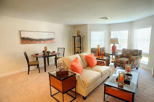 A cozy and stylish living room featuring a comfortable sofa with decorative pillows, a dining table, and warm lighting.