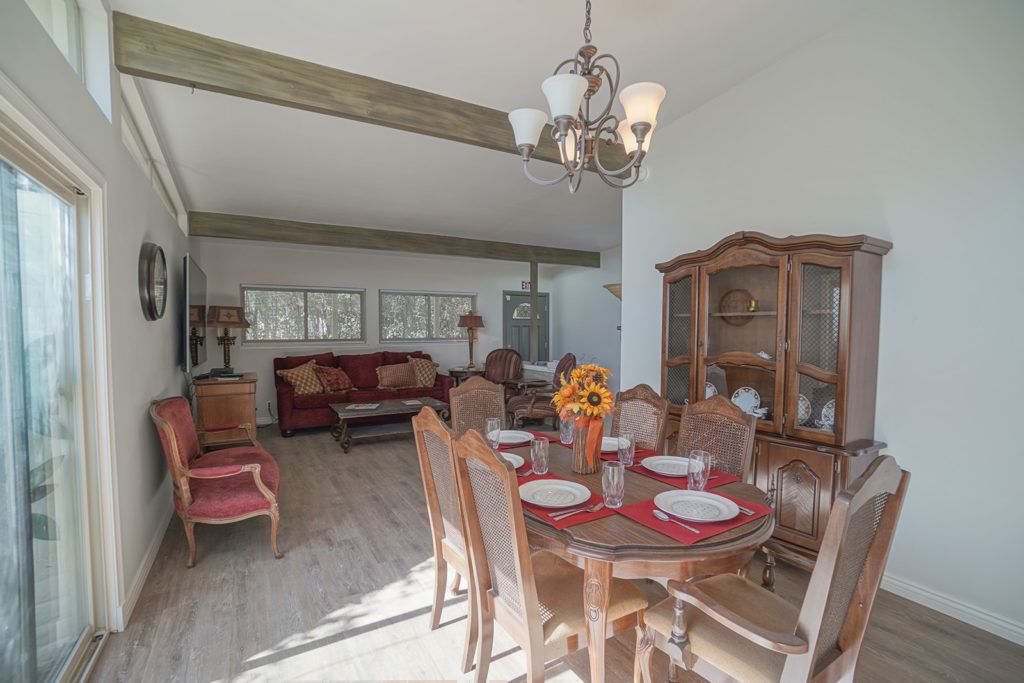 A cozy dining and living area featuring a wooden dining table set, a chandelier, and a comfortable sofa.