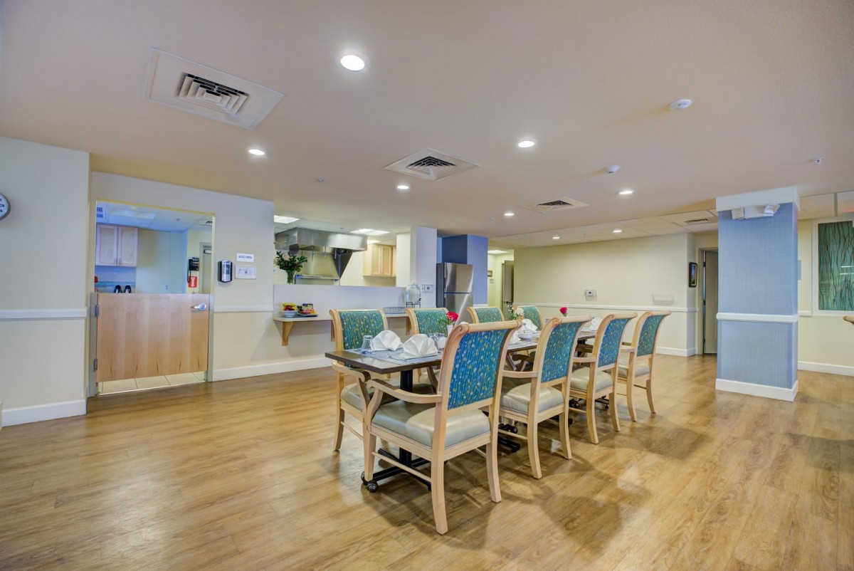 A modern dining room with a long table surrounded by chairs on a wooden floor.