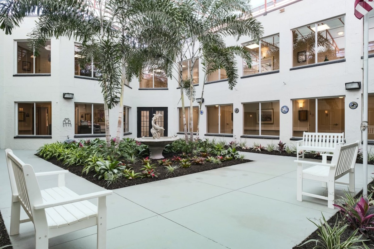 A spacious indoor courtyard with palm trees and seating areas, surrounded by modern architecture.
