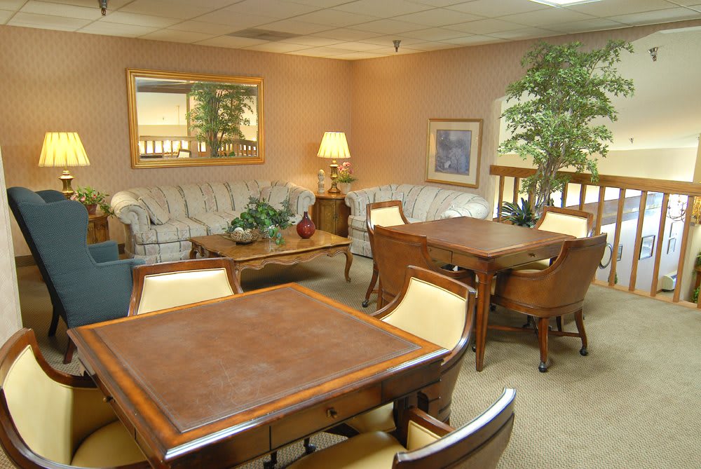 A cozy living room with a large sofa, coffee table, and a dining area featuring wooden tables and chairs.
