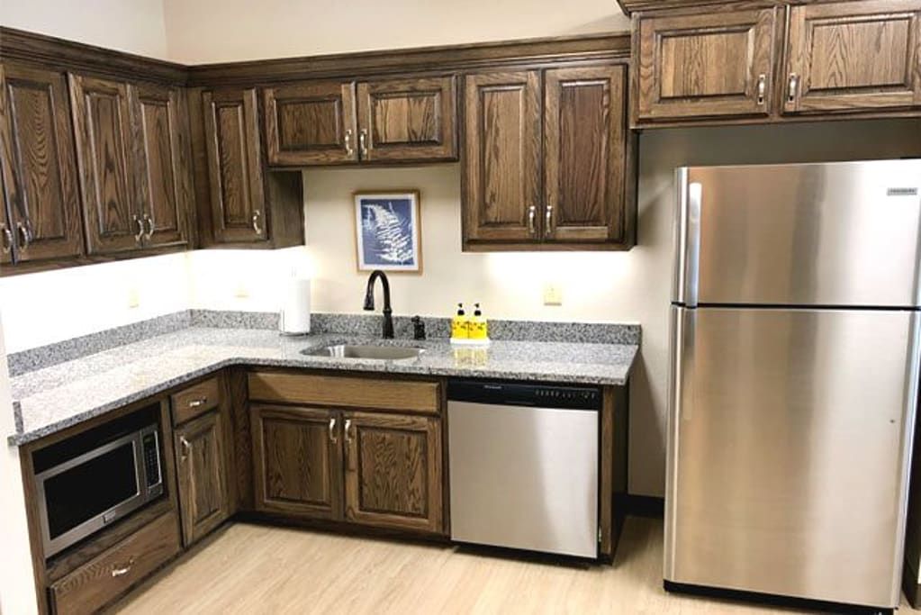 A modern kitchen with wooden cabinets, stainless steel appliances, and a well-organized countertop.