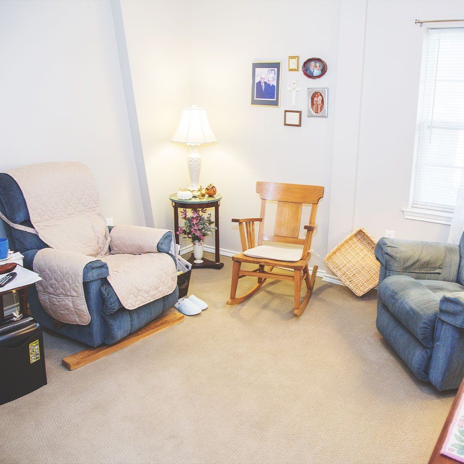 A cozy living room with two armchairs, a rocking chair, and a lamp.