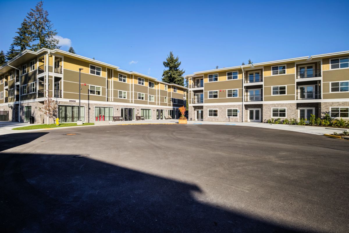 A modern apartment complex with multiple units and a large parking area.