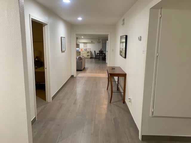 A well-lit hallway in a home with wooden flooring and simple furnishings.