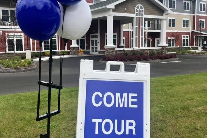 A sign with balloons invites people to tour the building.
