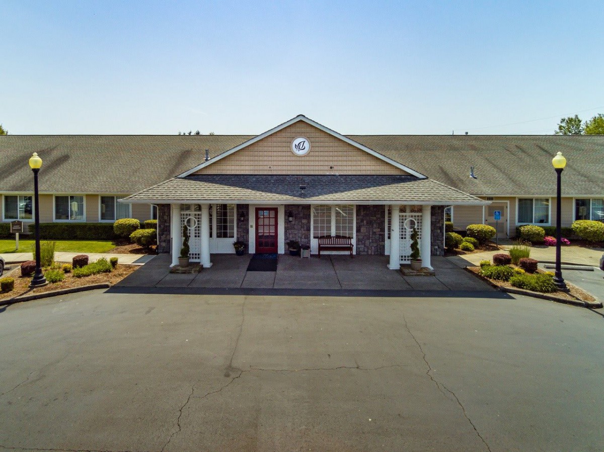 A suburban building with a central entrance and neatly landscaped surroundings.