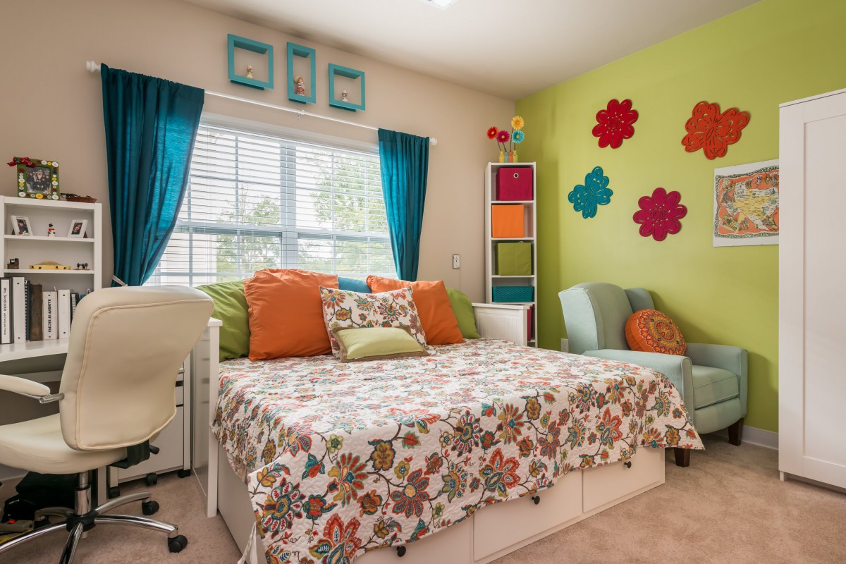 A vibrant and colorful bedroom with floral designs and decorative wall art.