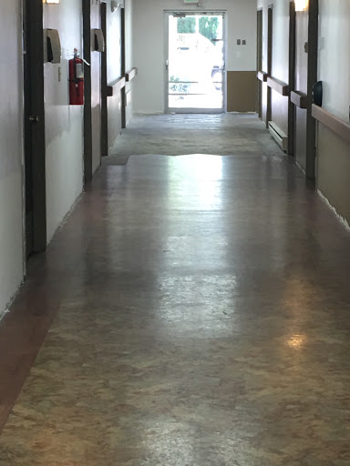 A long, empty hallway with polished floors and light streaming in from the entrance.