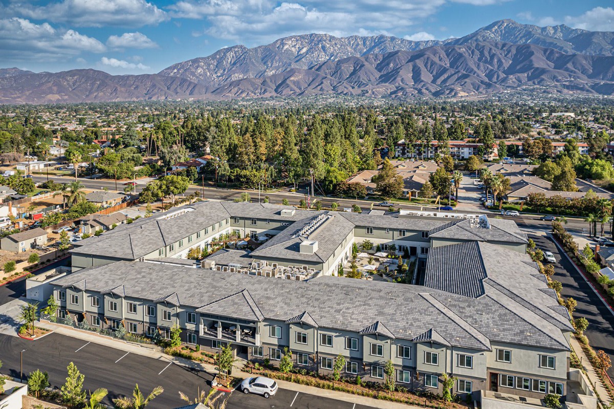 Aerial view of a suburban building complex set against a mountainous backdrop.