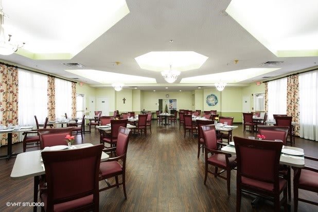 An elegant dining room with neatly arranged tables and chairs, featuring a wooden floor and soft ceiling lighting.