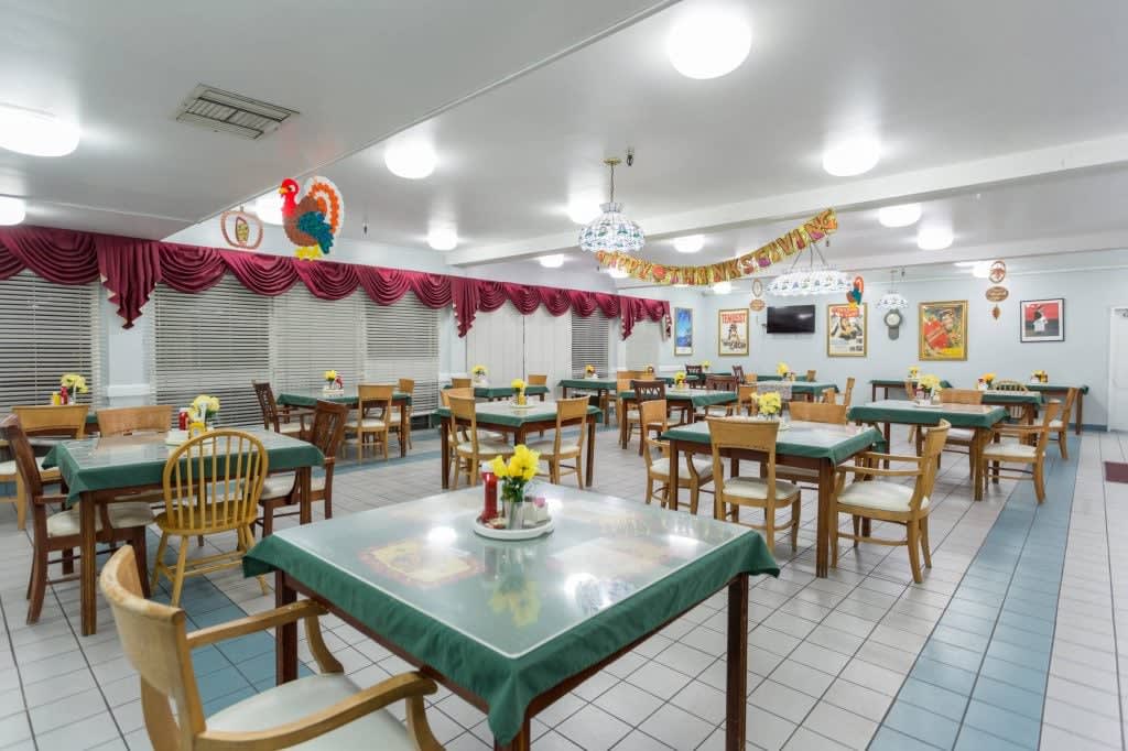 An interior view of an empty restaurant dining area with neatly arranged tables and chairs, adorned with decorative elements.