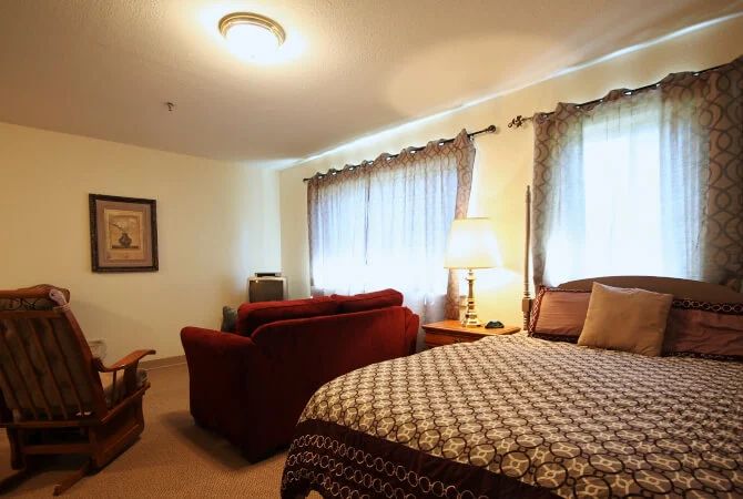 A cozy bedroom with a bed, couch, and warm lighting.