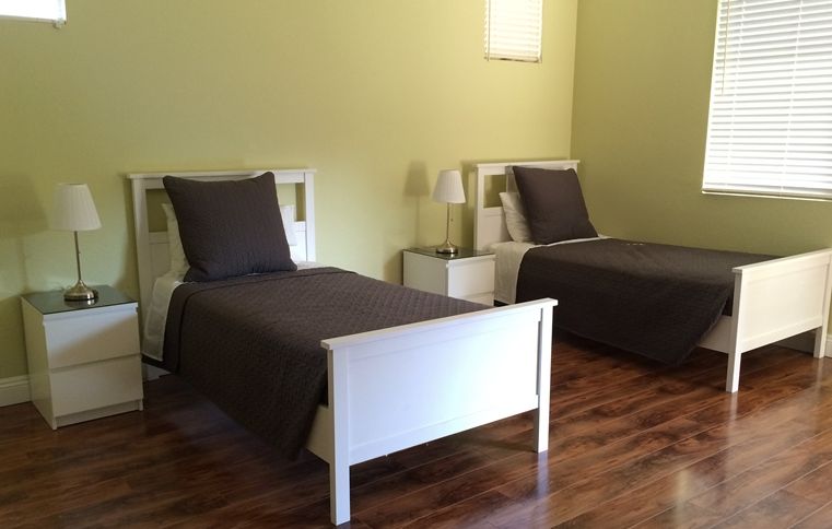 A minimalist bedroom with two twin beds and wooden flooring.