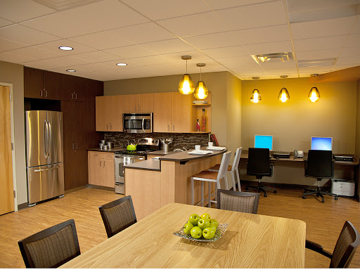 A modern kitchen and workspace area featuring sleek furniture, appliances, and a cozy dining setup.