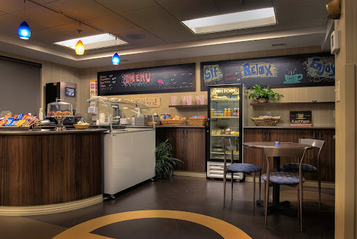 A cozy cafe interior featuring a service counter, display fridge, and comfortable seating.
