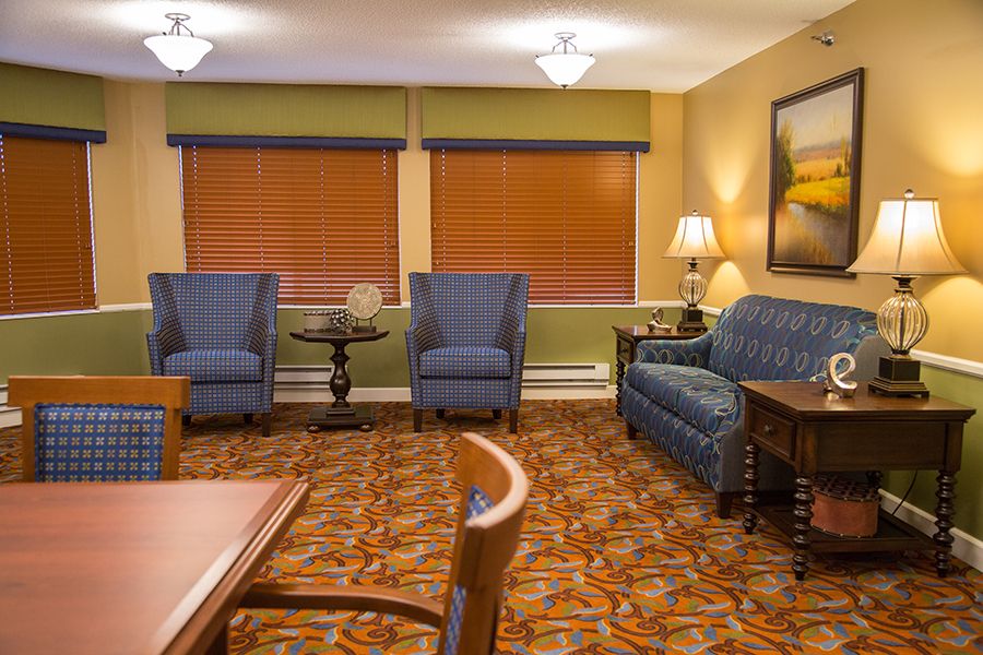 A cozy living room with comfortable seating, warm lighting, and patterned carpet.