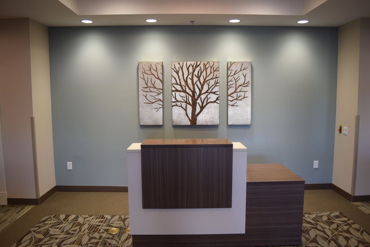 A modern reception area featuring a front desk with tree-themed artwork on the wall.