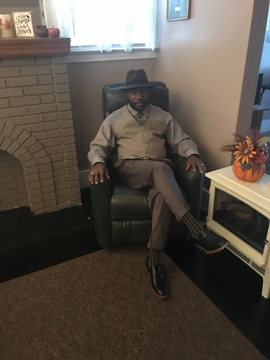 A well-dressed man sitting comfortably in a chair, exuding confidence and style.