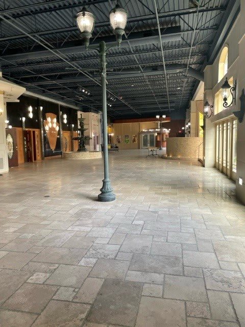 An empty indoor mall corridor with stores and decorative lighting.