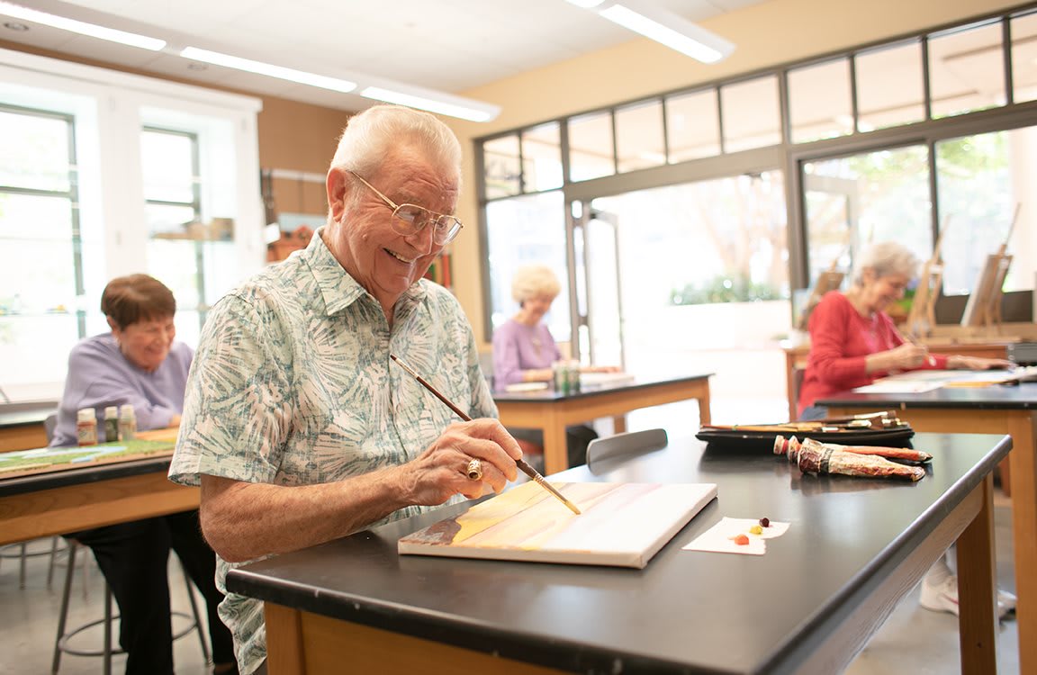 A senior man enjoying a painting session in an art class.
