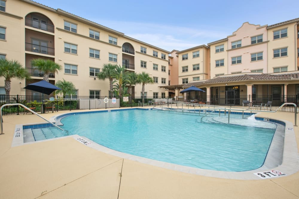 An outdoor swimming pool at a hotel with surrounding accommodation buildings.