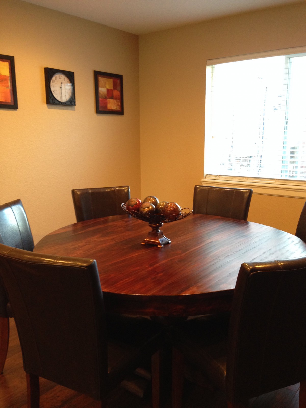 A cozy dining room with a round wooden table and chairs near a bright window.