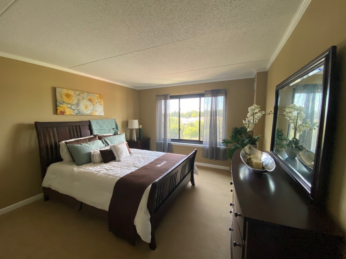 A cozy bedroom with a large bed, decorative pillows, and a window view.