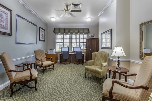 A cozy office space with chairs, computers, and a lamp.