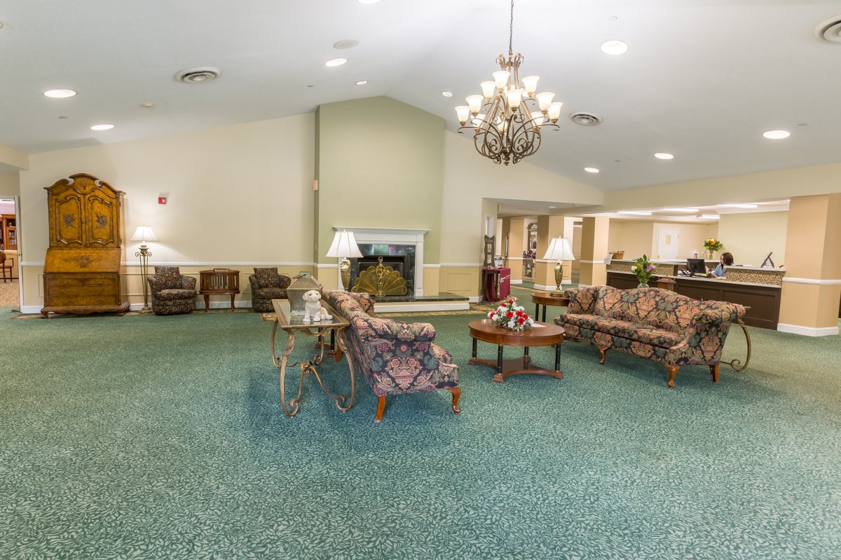 A spacious living room with seating arrangement and chandelier.