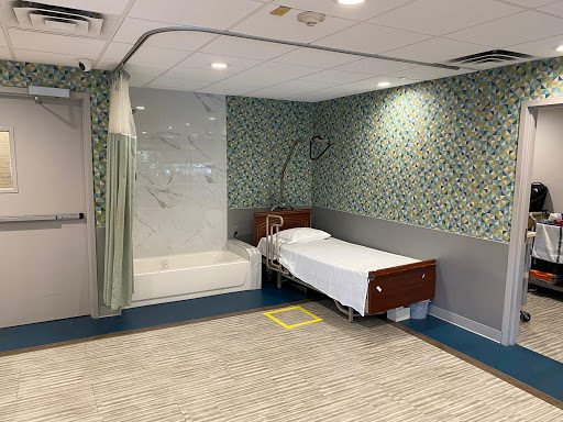 A clean and modern hospital room featuring a bed and a shower area.