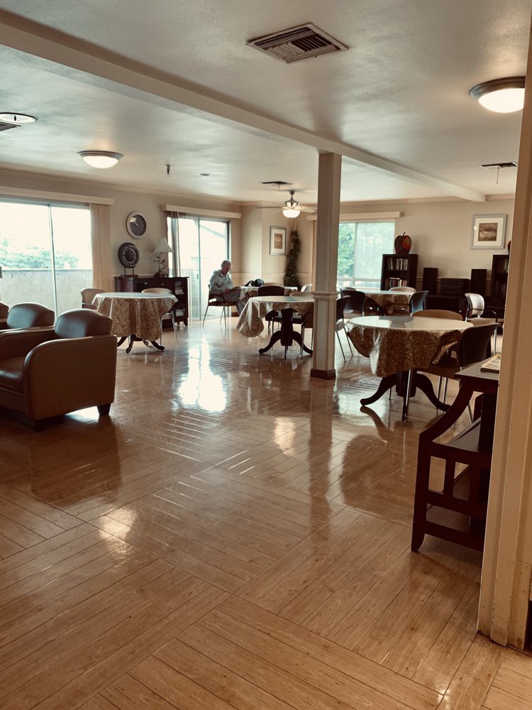 A spacious dining room with tables and chairs arranged neatly, featuring large windows that let in natural light.