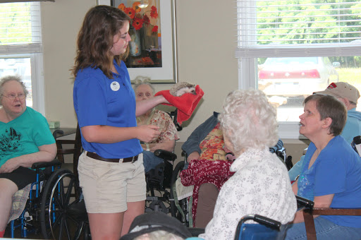 A volunteer engages with an elderly individual during an activity at a community center.
