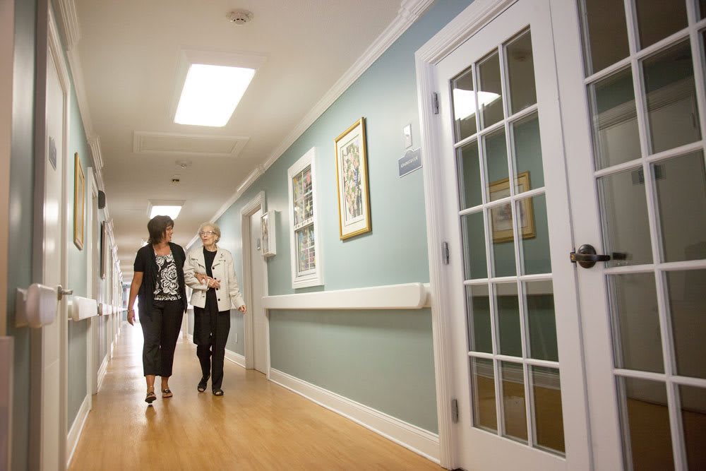 Two people walking and conversing in a well-lit hallway.