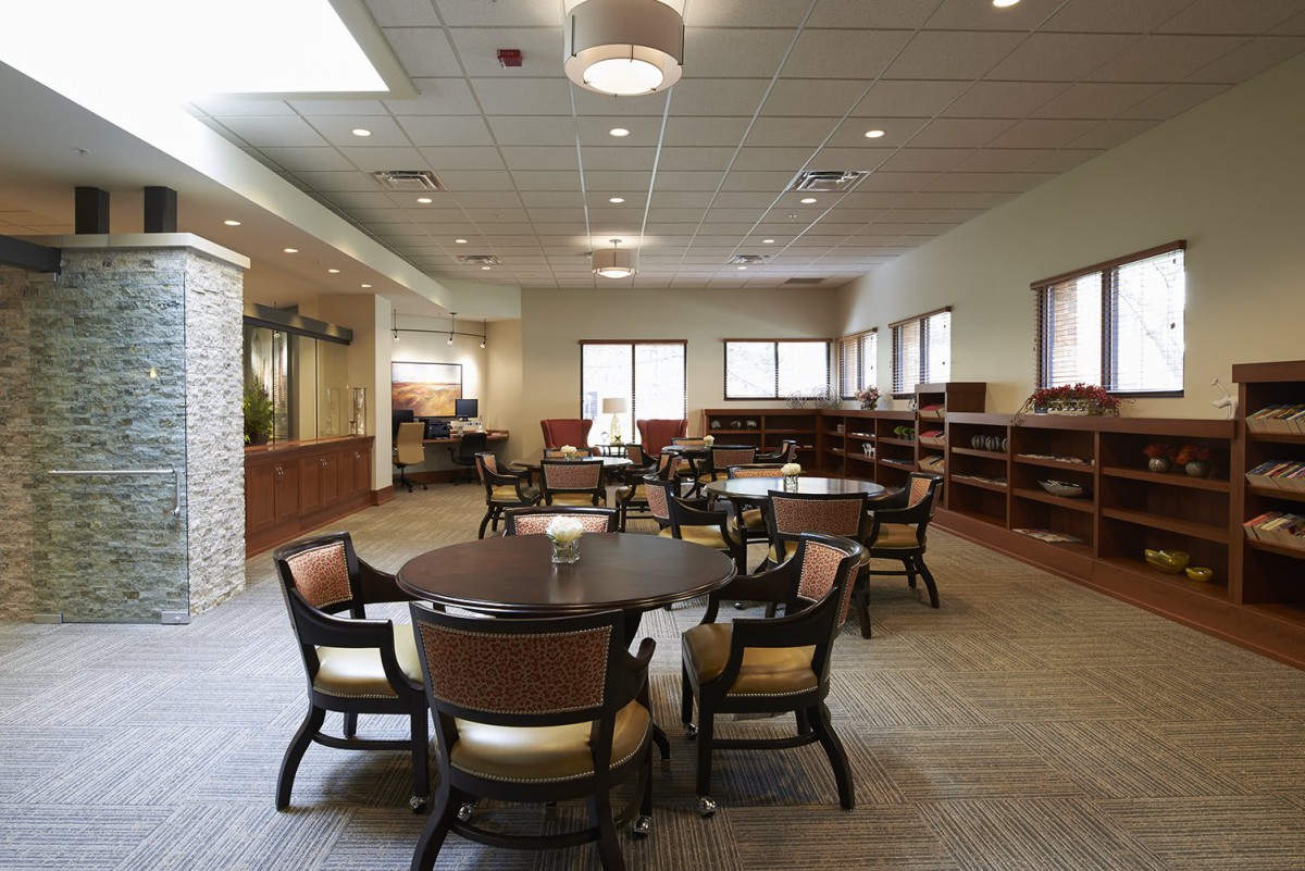 A spacious library interior with tables and chairs, surrounded by bookshelves.