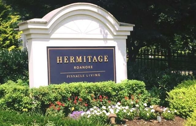 Entrance sign for Hermitage Roanoke surrounded by flowers.
