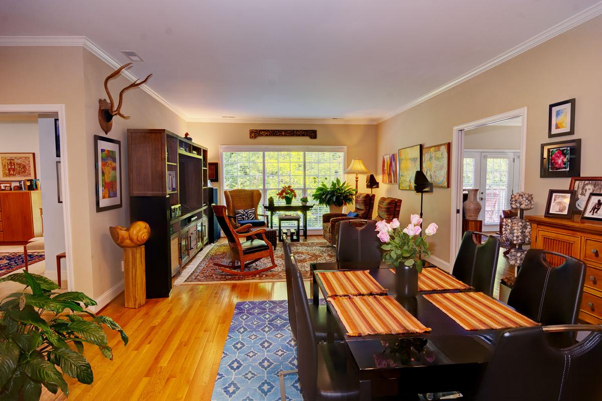 A cozy living room with a dining area featuring hardwood floors, eclectic decor, and ample natural light.