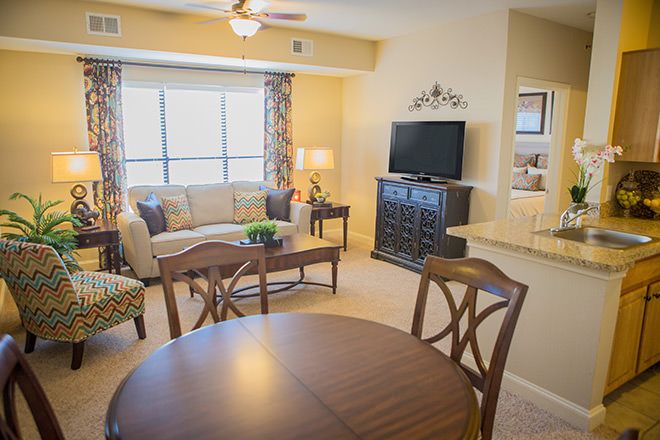 A cozy living room featuring a sofa, television, and a dining table with chairs.