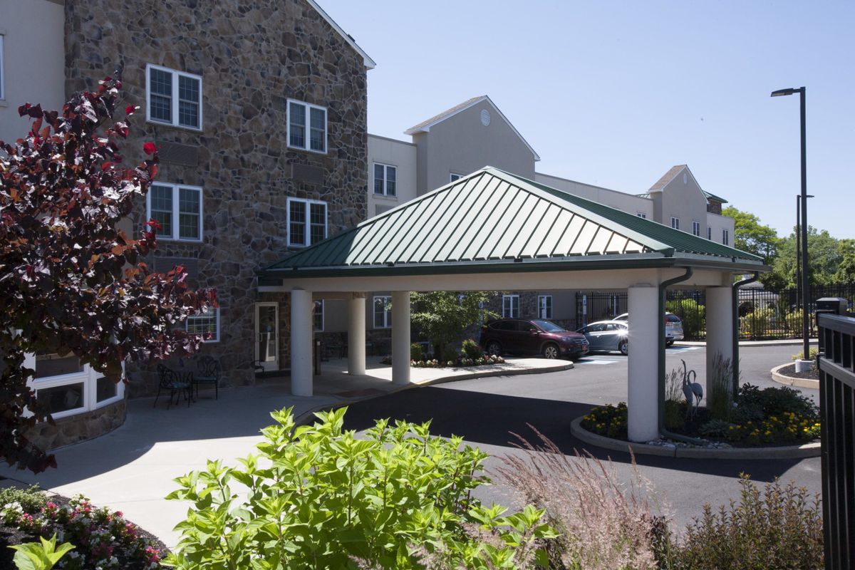 A residential building with a stone facade featuring a covered entrance and landscaped surroundings.
