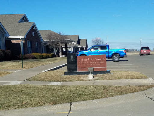 A scenic view featuring a building with a sign in front, accompanied by a blue truck parked nearby under a clear sky.