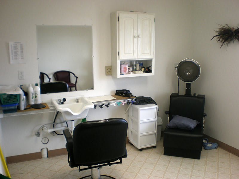 A cozy hair salon setup with a mirror, salon chair, sink, and hair dryer.